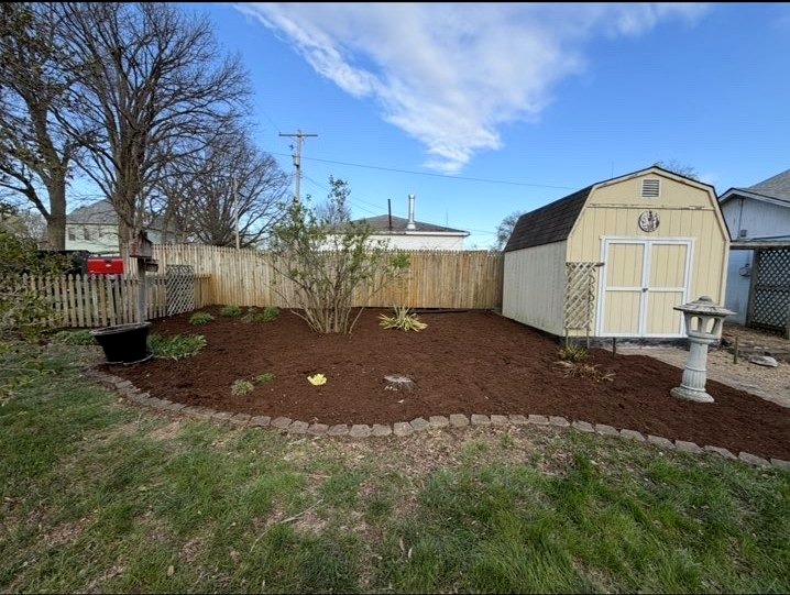 Freshly mulched backyard garden bed beside a shed